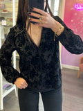 Blouse noire en voile transparent avec motifs floraux effet velours et manches longues légèrement volumineuses.