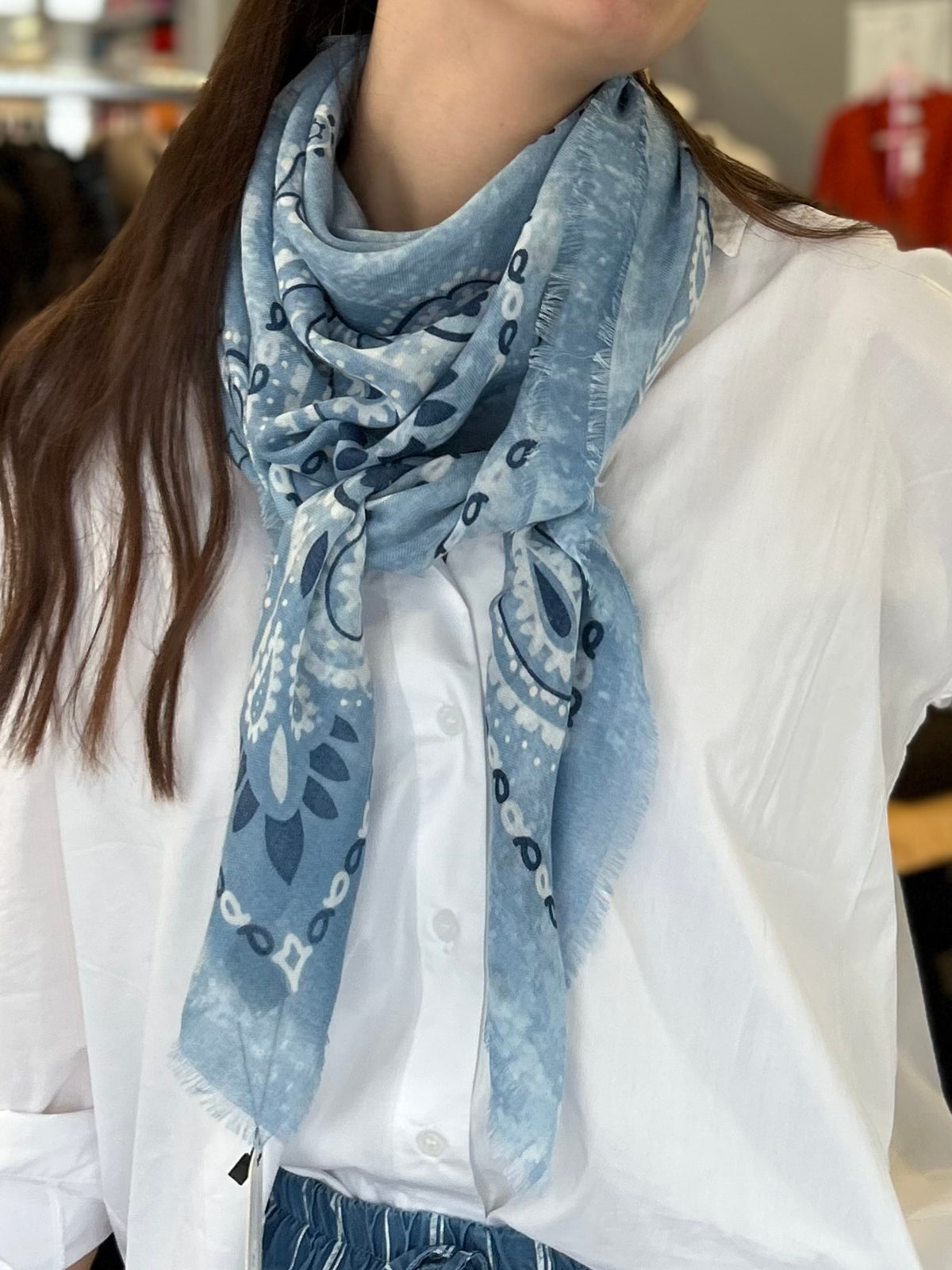Foulard carré à motif bandana porté autour du cou avec une chemise blanche, format 113x113 cm, style printemps chic.