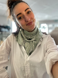 Foulard carré vert à motif bandana porté autour du cou avec une chemise blanche, format 113x113 cm, style printemps chic.
