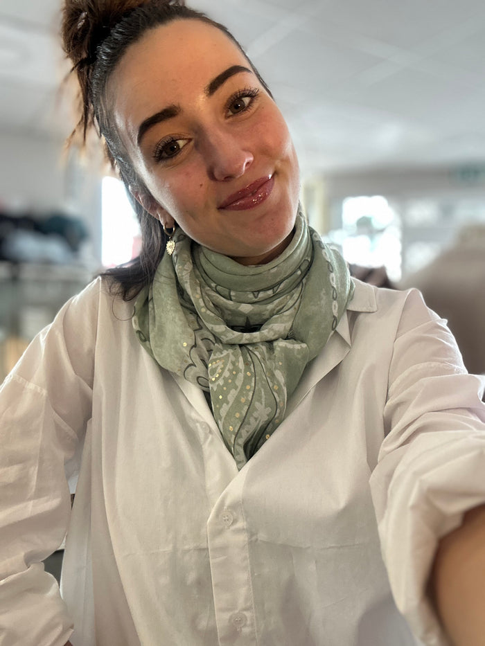 Foulard carré vert à motif bandana porté autour du cou avec une chemise blanche, format 113x113 cm, style printemps chic.