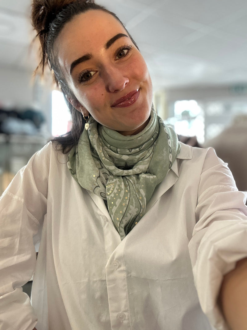 Foulard carré vert à motif bandana porté autour du cou avec une chemise blanche, format 113x113 cm, style printemps chic.