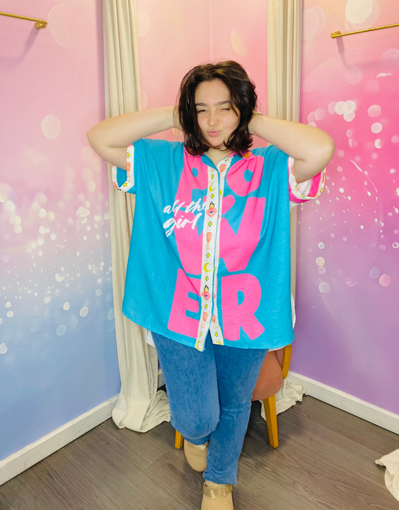 Femme souriante portant une chemise vintage aux couleurs vives (bleu turquoise et fuchsia) avec le mot 