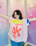La chemise "Ibiza Summer" portée par une jeune femme, qui pose avec une expression joyeuse, mettant en avant le design coloré et l'effet rétro de la chemise. Des couleurs de l'été, du soleil et de la plage se mélangent sur ce modèle oversize.