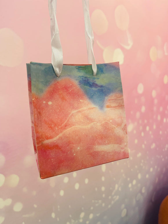 Petit sac cadeau rose et bleu à anse blanche – coffret surprise céleste et poétique, parfait pour offrir un bijou doré mystérieux et une attention parfumée.