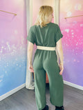 Combinaison pantalon à manches courtes droites, avec un col cache-coeur et une taille ceinturée ornée de sa ceinture à la boucle ronde qui souligne la silhouette.La ceinture est beige. La coupe fluide et droite offre un confort optimal tout en restant élégante. La combinaison est kaki mais il existe différents coloris. Cette pièce est idéale pour un look chic et décontracté. Egalement pour les jours de fêtes : un baptême, un mariage, une soirée mais aussi pour tous les jours. Belle idée cadeau.