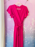 Combinaison pantalon à manches courtes volantées, avec un col cache-coeur et une taille ceinturée qui souligne la silhouette. La coupe fluide et droite offre un confort optimal tout en restant élégante. La combinaison est fuschia mais il existe différents coloris. Cette pièce est idéale pour un look chic et décontracté. Egalement pour les jours de fêtes : un baptême, un mariage, une soirée mais aussi pour tous les jours. Belle idée cadeau.