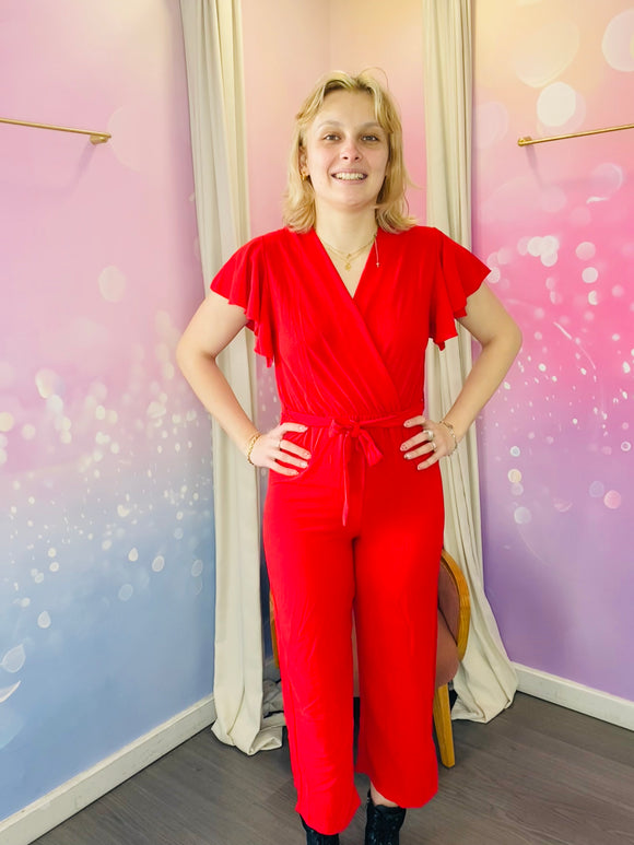 Combinaison pantalon à manches courtes volantées, avec un col cache-coeur et une taille ceinturée qui souligne la silhouette. La coupe fluide et droite offre un confort optimal tout en restant élégante. La combinaison est rouge mais il existe différents coloris. Cette pièce est idéale pour un look chic et décontracté. Egalement pour les jours de fêtes : un baptême, un mariage, une soirée mais aussi pour tous les jours. Belle idée cadeau.
