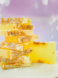 Savon naturel artisanal jaune avec pétales visibles, calendula & carotte, empilé sur assiette
