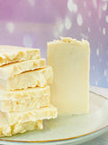 Savons blancs au lait d’ânesse empilés sur assiette, texture onctueuse et lisse