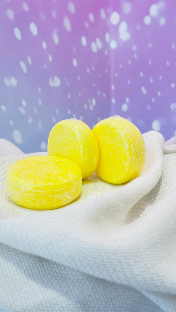 Shampoing solide jaune pour cuir chevelu sensible tenu dans une main, avec étiquette visible.
